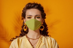 Fashionable model, woman wearing trendy outfit with protective face mask, stylish yellow earrings, chain necklace. Summer fashion during quarantine of coronavirus outbreak. Copy, empty space for text