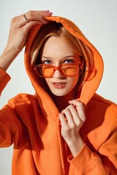 Fashion portrait of confident woman wearing trendy orange color sunglasses, oversized hoodie