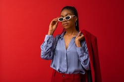 Fashionable Black woman wearing classic satin shirt, trendy sunglasses. Fashion studio portrait. Copy, empty space for text 
