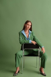  Fashionable beautiful confident woman wearing trendy suit blazer, classic trousers, blue office shirt, zebra print pointed toe shoes, posing on green background. Full-length studio portrait