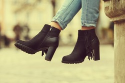  Elegant outfit. Closeup of stylish black suede ankle boots. Fashionable girl on the street. City lifestyle. Female fashion. Toned