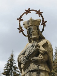 A statue of a holy man with a cross in an old cemetery.