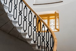 Ornate staircase with wrought iron railing and wooden window