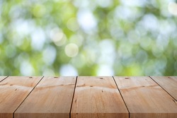 Close-up empty wooden plank long table top on vintage style for put product and anything display with outdoor theme on blurred greenery background