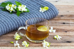 herbal healthy drinks hot lemon tea health care for cough sore with lemon slice ,jasmine flowers and knitting wool scarf of lifestyle woman relax winter arrangement flat lay style on background wooden