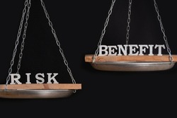 Risk and benefit reward concept. Scales on black background close up.