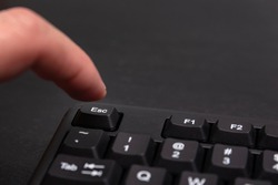 Finger reaches for the Esc button. Black keyboard escape key