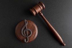 Music symbol treble clef and judge gavel on black background. Music copyright infringement. Music piracy