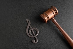 Treble clef next to gavel on black background. Music copyrights. Music piracy concept