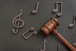 Judges gavel surrounded by treble clef and notes on black background. Violation of music license and copyright. Music piracy