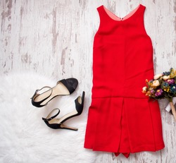 Red dress, black shoes and bouquet. Imitation fur on a wooden background, fashionable concept, top view