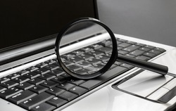 Magnifying glass on the laptop keyboard. 