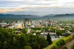 The skyline of downtown Asheville, North Carolina at sunset with mountains in the background