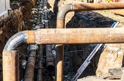 Replacement of heating pipes and modernization of the heating system in city. Construction works on large iron pipes at a depth of excavated trench