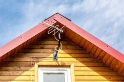 Aerial antenna on the roof of old wooden house against the sky
