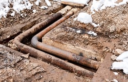 Replacement of heating pipes and modernization of the heating system. Repair of old rusty metal pipes. Construction works on iron pipes at a depth of excavated trench