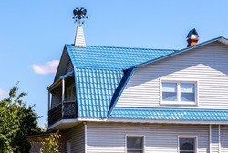Metal weather vane in the form of a double-headed eagle on the roof of the house