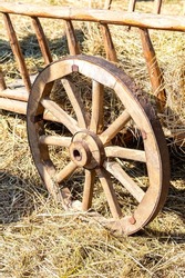 Old wooden farm wagon with traditional wheels made of wood and an rusty iron rim. Vintage wooden carriage wheel with a rusty rim from an old cart