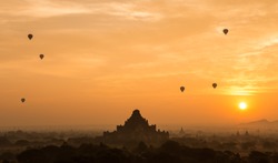 Hot air balloon float over silhouette ancient temple with scenic sunrise orange sky background at Old Bagan , Myanmar