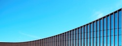 Fragment of the mirror wall of the building against the blue sky.
office building covered with glass. Place for an inscription, advertising. Panorama.