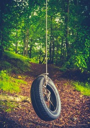 Retro Style Childhood Image Of A Tyre Swing Deep In A Forest