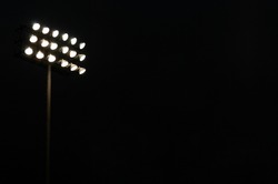 Stadium flood lights on a sports field at night with copy space