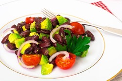 Salad with avocado, beans, cherry tomatoes, red onion and vegetable oil. Studio Photo