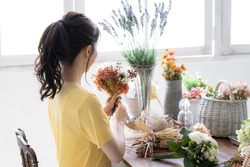 Asian young woman with flower arrangement.