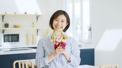 A smiling Asian woman with a bouquet