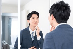 Young Asian businessman looking in the mirror