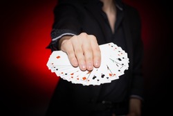 Card dealer shows fanned deck of playing cards. Your choose.  Red and black background.