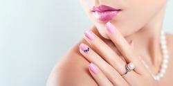Nail art and design. Beautiful woman wearing make-up and pearl jewellery showing pink manicure with gems. Beauty fashion model. Skin care. Banner