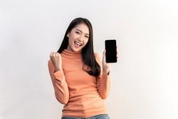Portrait photo of young beautiful Asian woman feeling happy or surprise shock and holding smart phone with black empty screen on white background can use for advertising or product presenting concept.