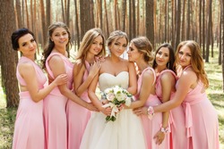Love of bride and bridesmaids. Wedding group portrait, bride holding wedding bouquet, bridesmaids embracing bride and smiling