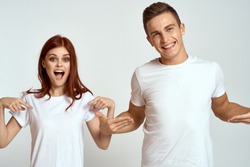 cheerful young couple in white t-shirts on a light background, logo                               