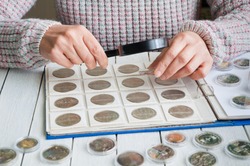 Woman looks at the coins through a magnifying glass