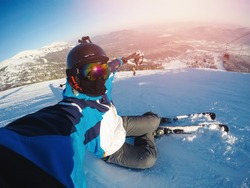 Winter extreme sport with selfie action camera. Man rides on slopes skis in protective helmet.