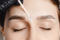 Master wax depilation of eyebrow hair in women, brow correction.