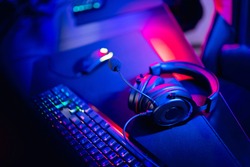 Professional gamers room with headphones microphone for cyber esports and video games on neon background of gaming monitor.