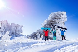 Three friends snowboarders, skier stands with ski and snowboard background blue sky with sun light. Concept extreme freeride Sheregesh resort.