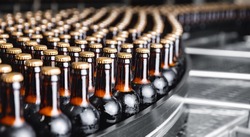 Glass bottles of beer on dark background. Concept banner brewery plant production line.