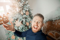 Happy smile young man takes selfie photo on background Christmas interior house with sunlight.