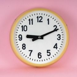 Vintage industrial wall clock. Analog white clock. Retro antique clock in bright pink color background isolated. 