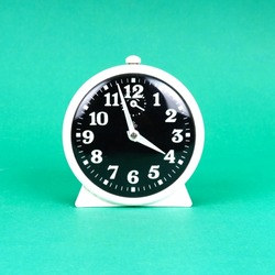Vintage alarm clock. Analog table clock. Retro antique alarm clock in bright green color background isolated. Classic design. Vintage ticking clock with alarm bell.