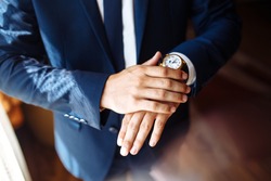Men's wrist watch, the man is watching the time. Businessman clock, businessman checking time on his wristwatch. Groom's hands in a suit adjusting wristwatch, wedding preparations, groom accessories.