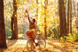 Happy young woman having fun and playing with autumn yellow leaves in autumn park.  Relaxation, enjoying, solitude with nature.