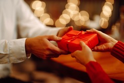 Exchange of gifts. Man gives to his woman surprise a gift box with red ribbon.Young loving couple celebrating Valentines Day. Romantic day. Winter holidays.
