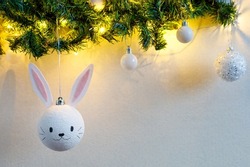 Handmade christmas ball with ears in form of bunny hanging on the christmas tree. Happy Chinese new year of the rabbit zodiac sign. Symbol of the year 2023.
