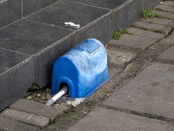 An old blue water meter cover made from plastic at a parking lot in front of a building in Sentul, West Java, Indonesia
