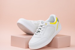 new trendy white sports sneaker on a stand on a pink background